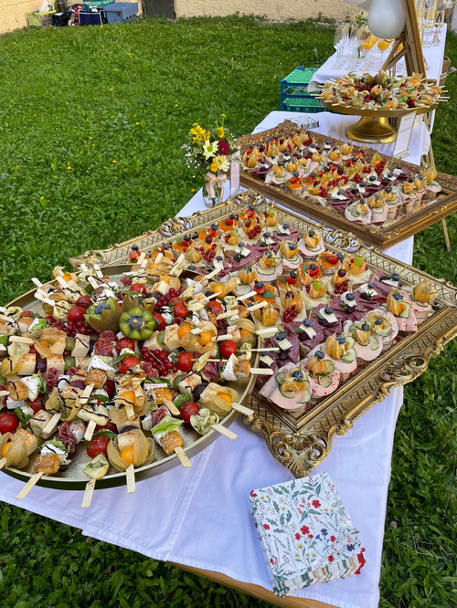 KI generiert: Ein Buffet mit verschiedenen dekorativen Häppchen auf Tabletts im Freien.