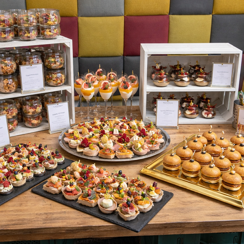 KI generiert: Verschiedene Canapés und Mini-Burger auf Tabletts, dekorativ auf einem Tisch präsentiert.