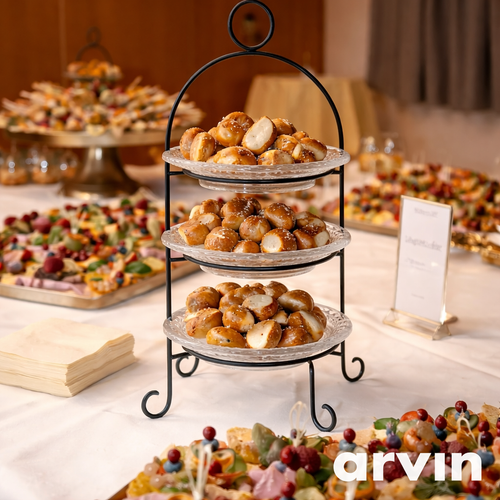 KI generiert: Ein Buffet mit dreistufiger Etagere voller Gebäck. Text: "arvin".