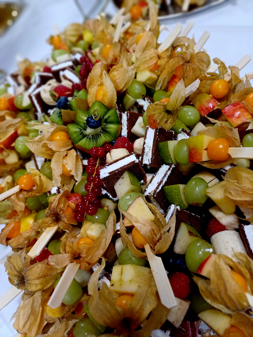 KI generiert: Obst- und Kuchenspieße mit Physalis, Kiwi und Beeren dekoriert.