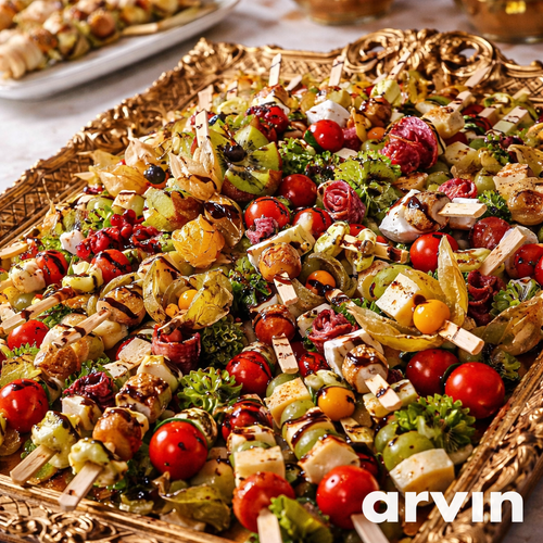 KI generiert: Bunte Antipasti-Spieße auf einem dekorativen Tablett mit frischen Zutaten, Schriftzug: "Arvin".