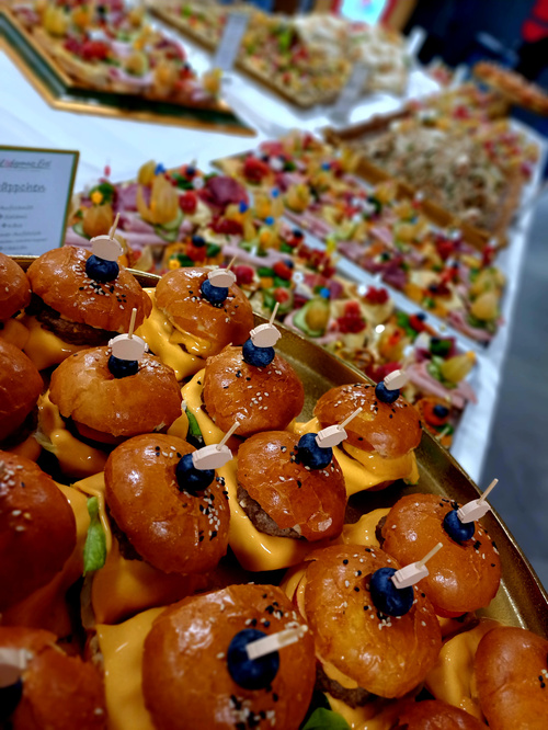 KI generiert: Ein Buffet mit Mini-Burgern und Fingerfood, hübsch dekoriert für eine Veranstaltung.