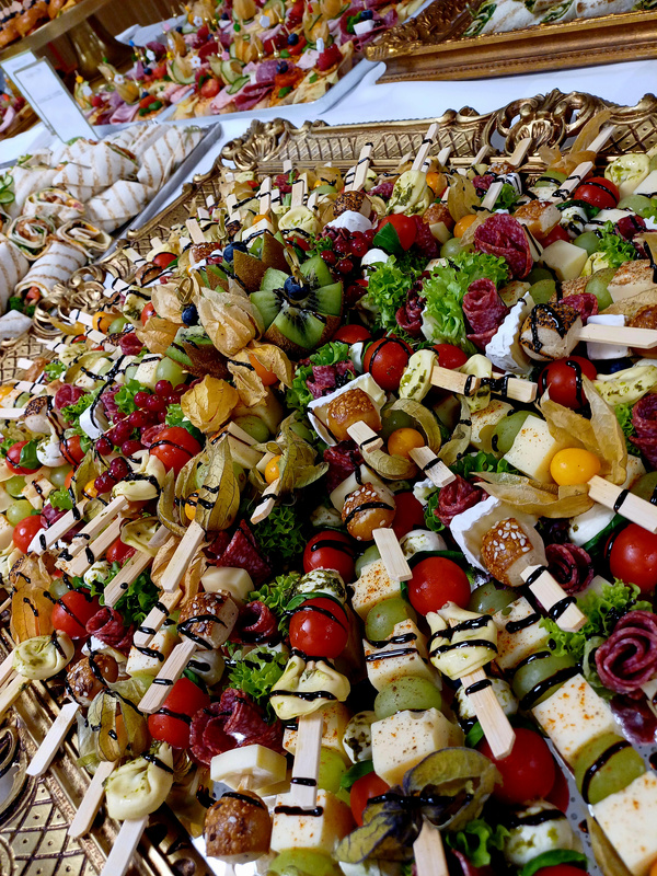 KI generiert: Bunt dekorierte Fingerfoods auf Spießen, mit Früchten und Gemüse, üppig auf einem Tisch angerichtet.