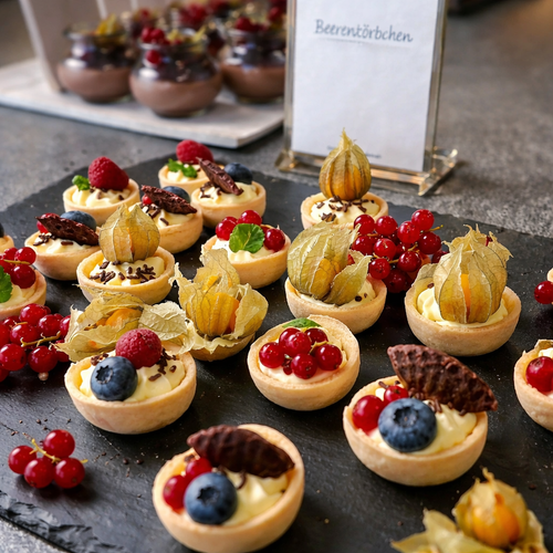 KI generiert: Kleine Törtchen mit Beeren und Physalis auf einer Platte. Text: "Beerenkörbchen".