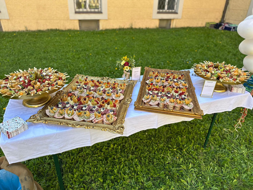 KI generiert: Ein dekorierter Tisch mit einer Auswahl an Fingerfood auf goldenen Tabletts im Freien.