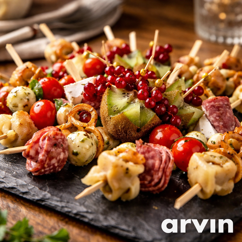 KI generiert: Bunte Vorspeisenplatte mit Spießen aus Käse, Salami, Kirschtomaten, Kiwi und Beeren. Text: "arvin".