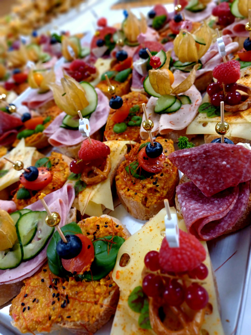 KI generiert: Verschiedene Canapés mit Käse, Wurst, Obst und Gemüse aufgespießt und dekorativ angerichtet.